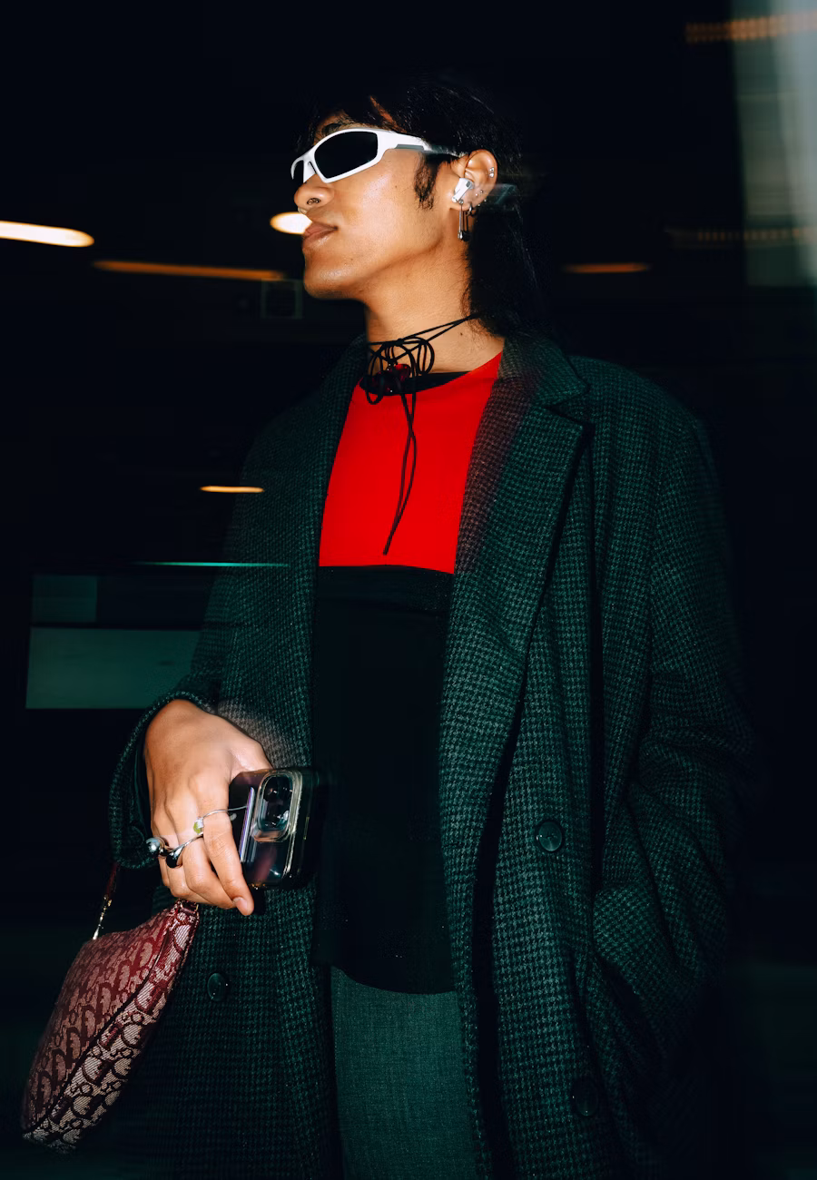 Woman in a black coat and sunglasses holding a purse