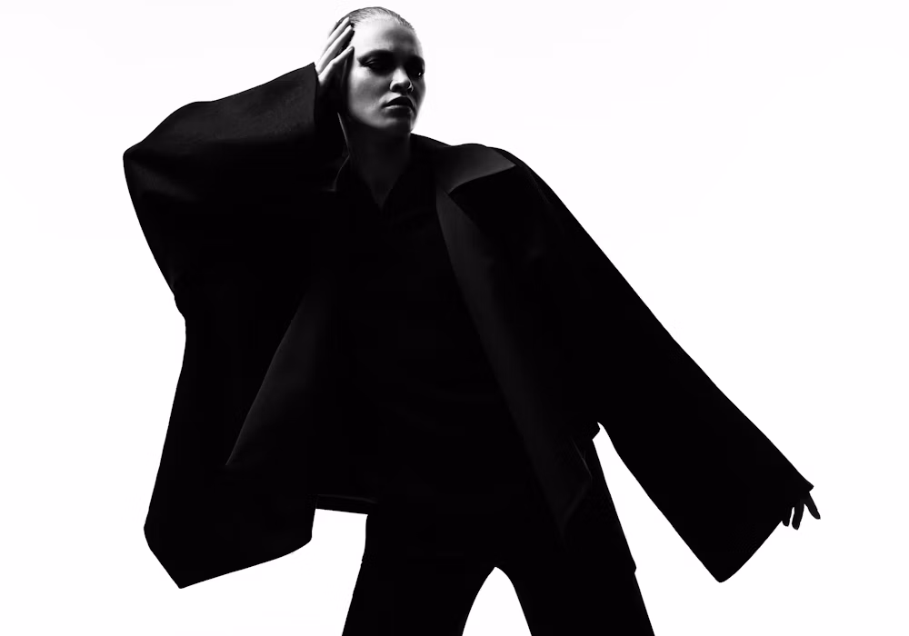 Person in a wide-sleeved black jacket, silhouette against white
