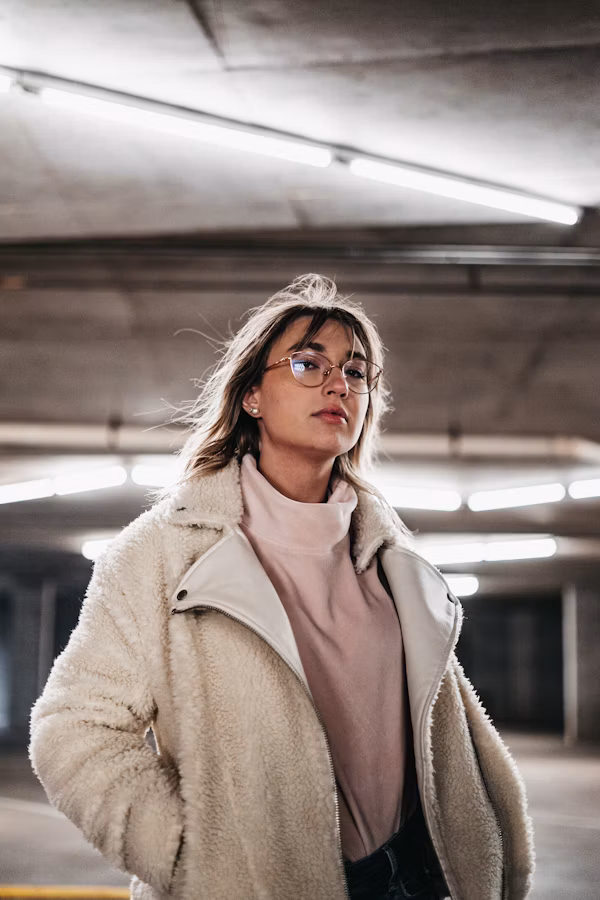 Woman in a brown coat wearing black-framed eyeglasses